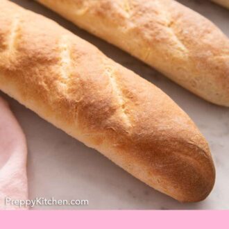 Pinterest graphic of a close up view of a couple loaves of French bread.