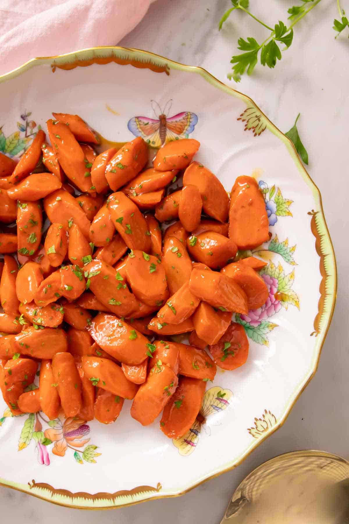 Overhead view of a plate of glazed carrots with chopped parsley garnish.