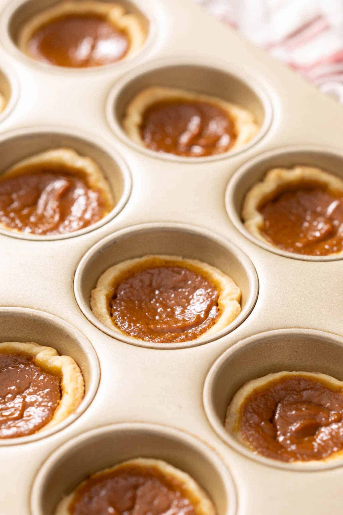 A muffin tin with mini pumpkin pies.