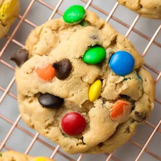 Overhead view of a monster cookie on a cooling rack with additional cookies off to the side.