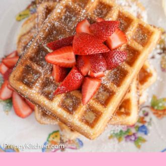 Pinterest graphic of an overhead view of strawberries on top of a stack of waffles dusted with powdered sugar.