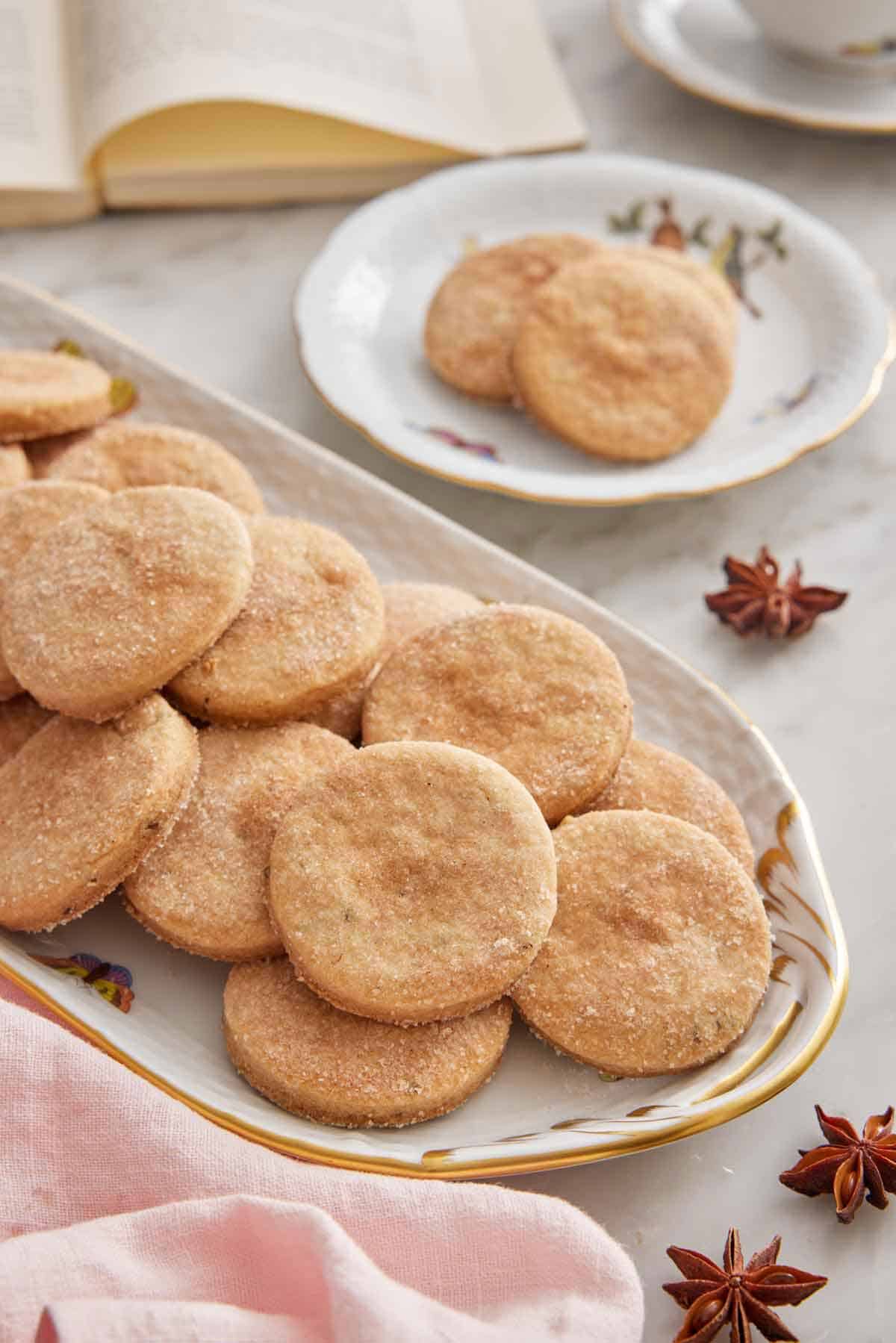 A platter of biscochitos with a plate with a couple in the background.
