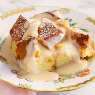 A serving of bread pudding on a plate with vanilla sauce on top.