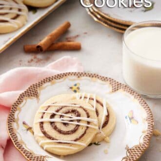 Pinterest graphic of a plate with two cinnamon roll cookies along with a glass of milk and a platter of more cookies in the background.