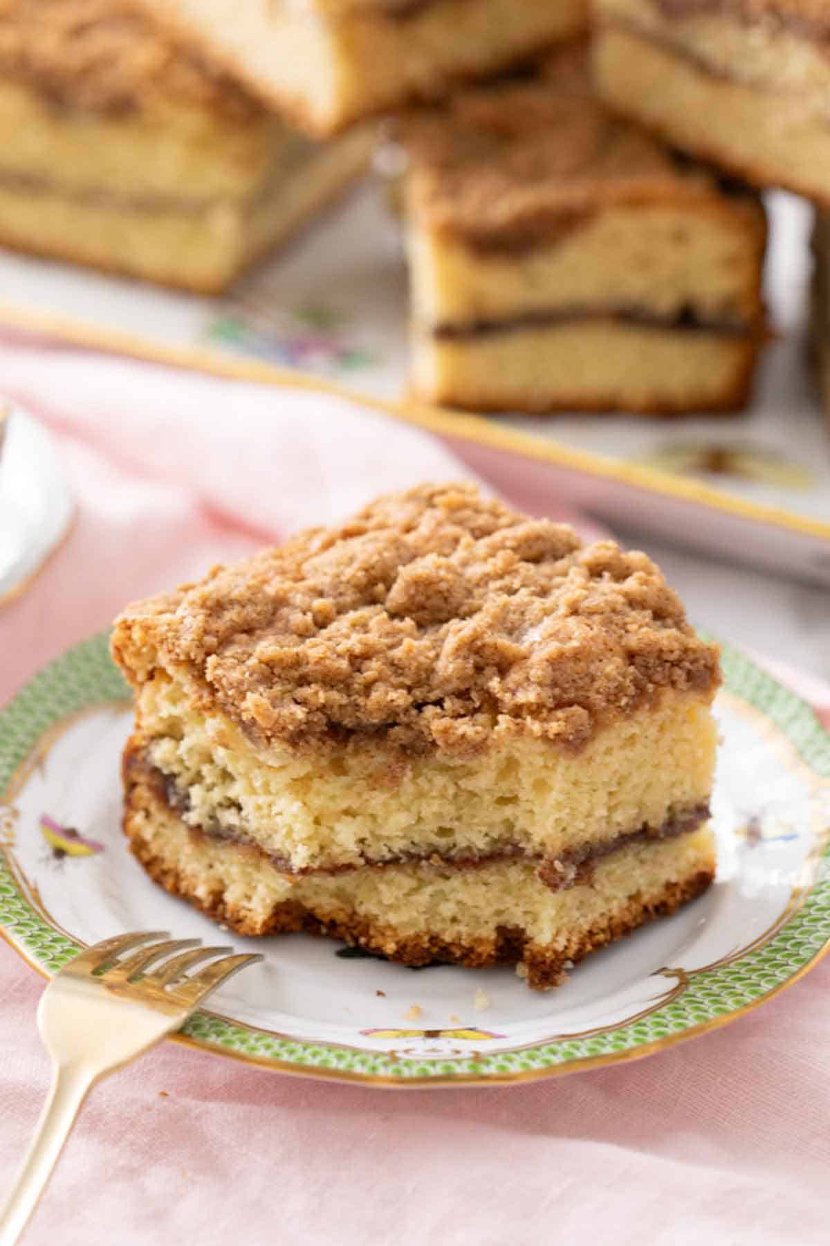 A piece of coffee cake with a bite taken out and a fork propped on the plate.