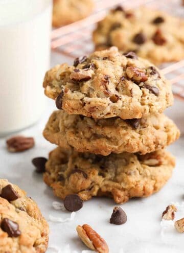 A stack of three cowboy cookies with additional ingredients scattered around.