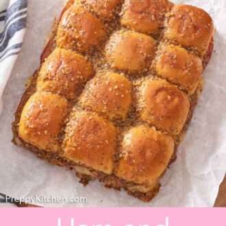 Pinterest graphic of overhead view of ham and cheese sliders before being sliced on a lined serving board.