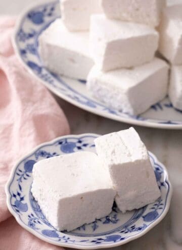 A plate with two homemade marshmallow recipe with a platter in the background.
