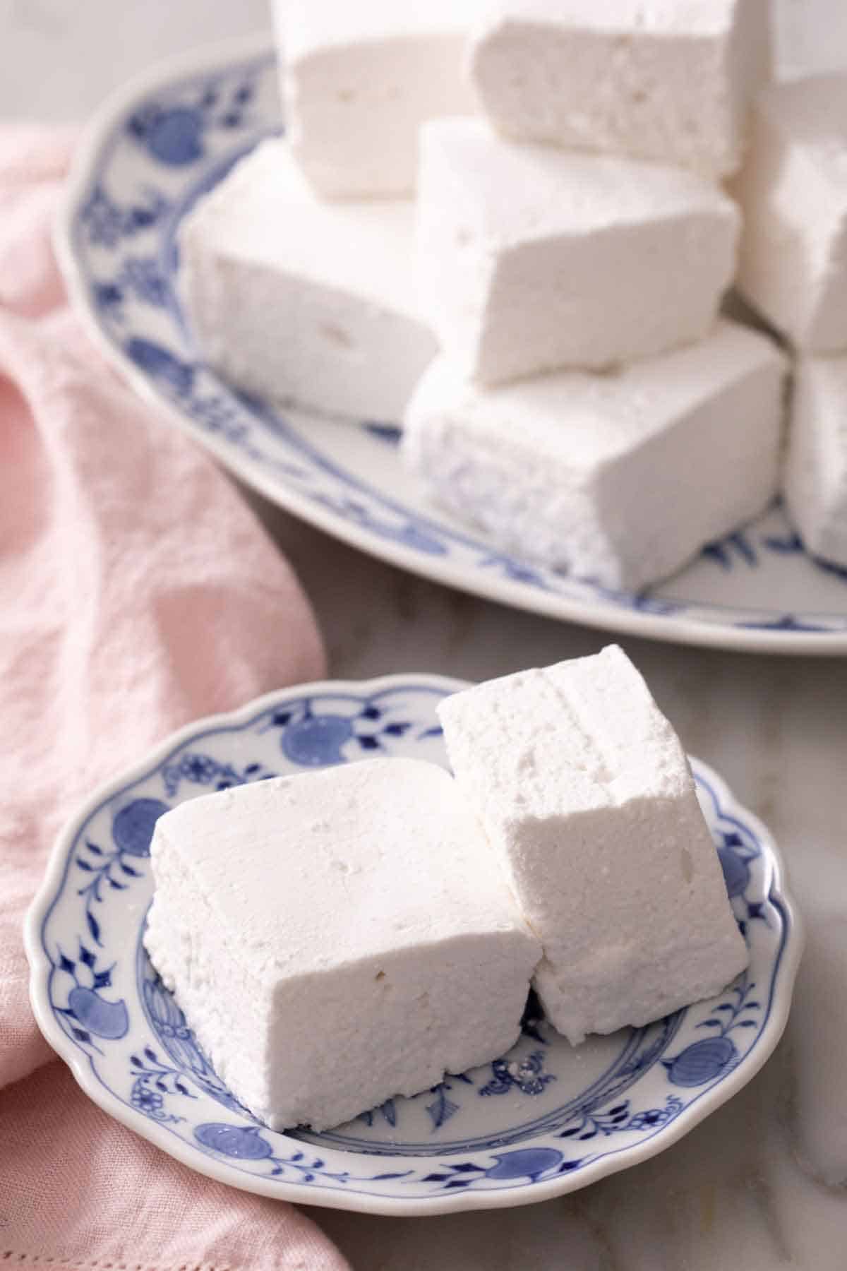 A plate with two homemade marshmallow recipe with a platter in the background.