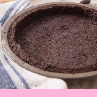Pinterest graphic of an Oreo pie crust in a pie pan with some crushed Oreos and some butter in the background.