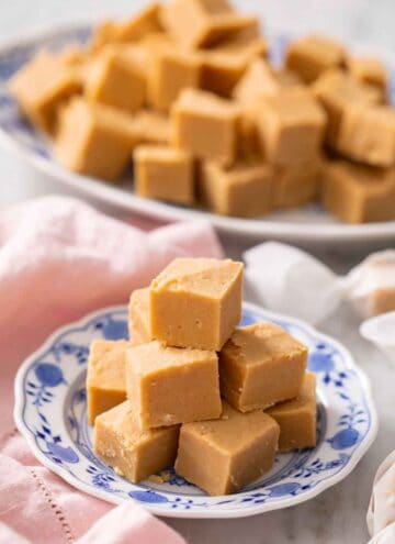 A plate with a pile of peanut butter fudge with a platter in the background.