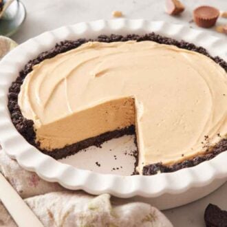 A baking dish with a peanut butter pie with a large slice taken out.