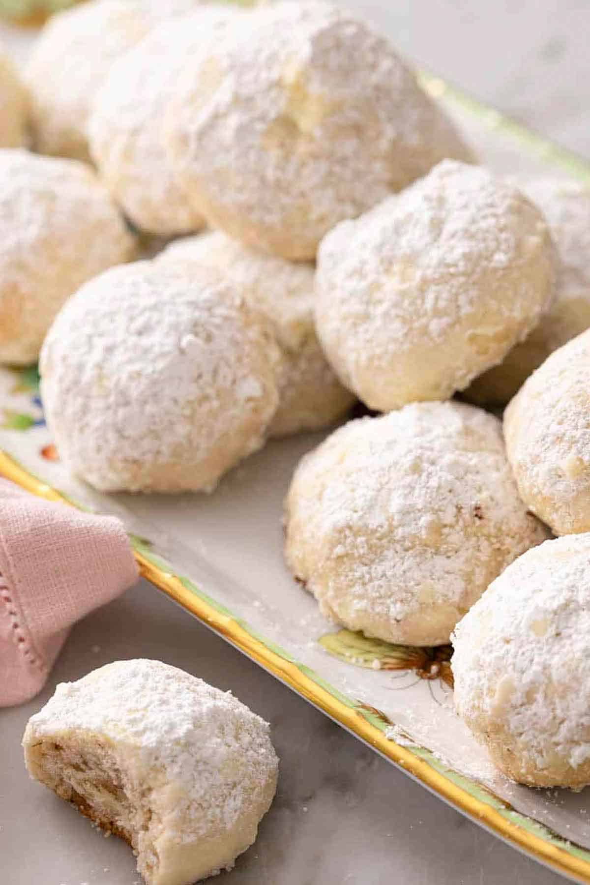 A platter of Russian tea cakes with one in front with a bite taken out.