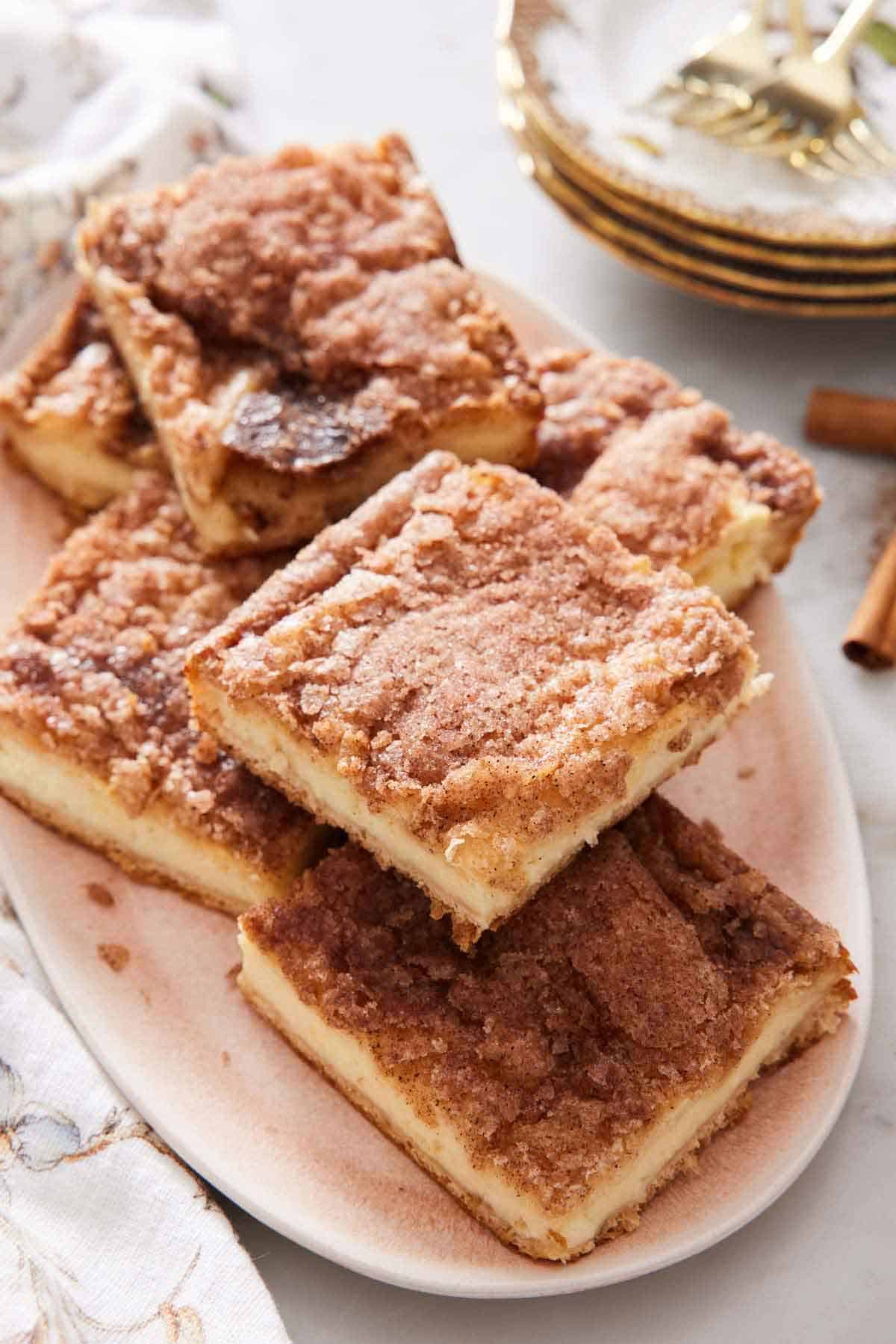A platter of sopapilla cheesecake cut into squares with a stack of plates in the background.