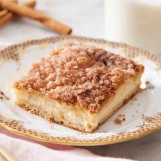 A square slice of sopapilla cheesecake with a glass of milk in the back.