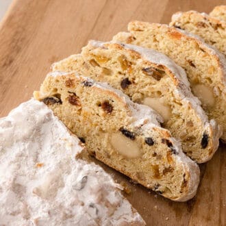 A cutting board with a stollen with five slices cut from it.
