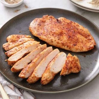 A plate with two air fryer chicken breasts, one sliced.