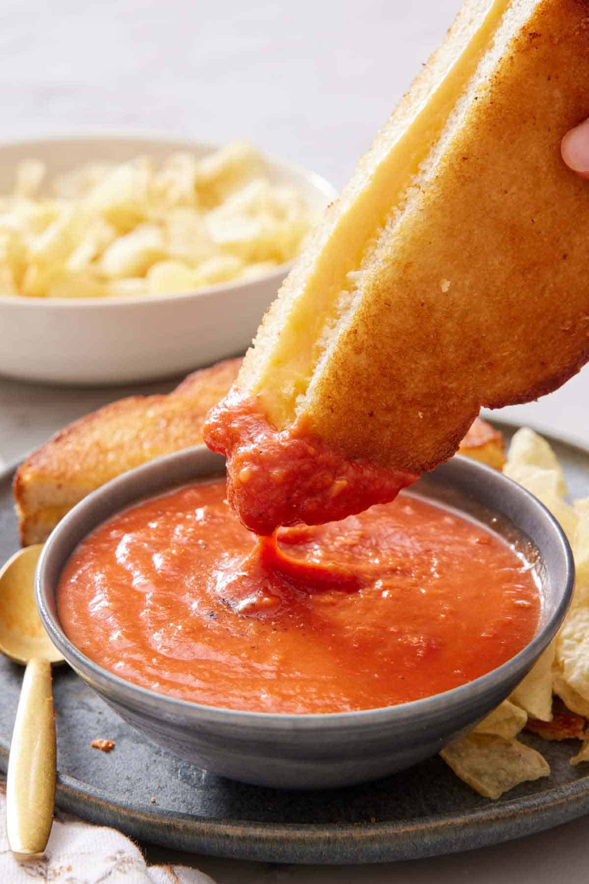 Half an air fryer grilled cheese dipped into tomato soup.
