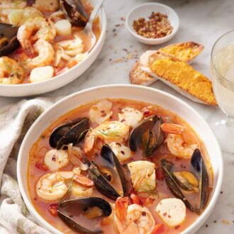 Pinterest graphic of bowls of bouillabaisse and bread with rouille spread on it in the background along with a bowl of rouille.