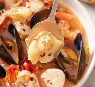 Pinterest graphic of a spoon lifting up shrimp from a bowl of bouillabaisse.