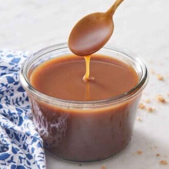 A spoon lifting up butterscotch in a jar and letting it drizzle.