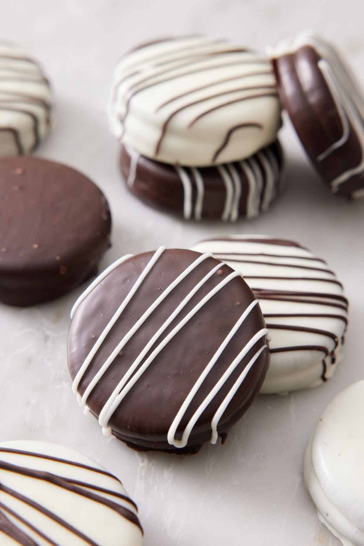 Multiple chocolate covered oreos scattered on a counter.