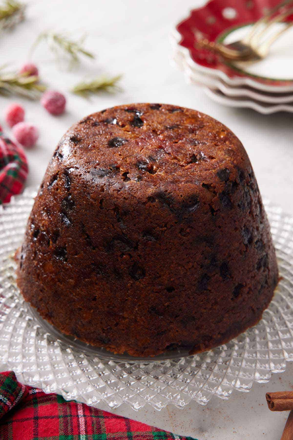 A platter with a Christmas pudding. Stack of plates in the background.