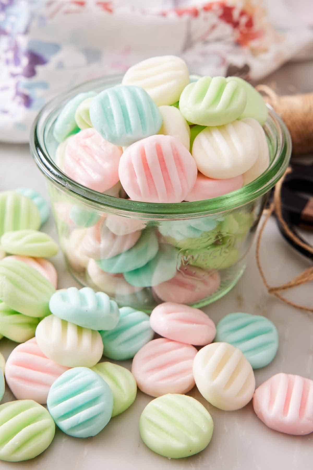 A jar of cream cheese mints with more scattered around it.