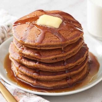 A plate with a stack of gingerbread pancakes with butter and syrup.
