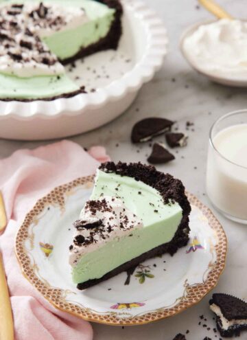 A slice of grasshopper pie on a plate with the rest in a baking dish in the background.