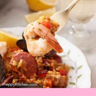 Pinterest graphic of a fork holding up a shrimp from a plate of paella.