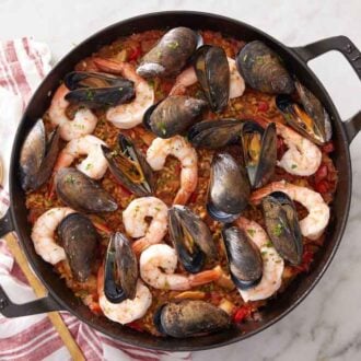 Overhead view of paella with a serving spoon and napkin beside it.