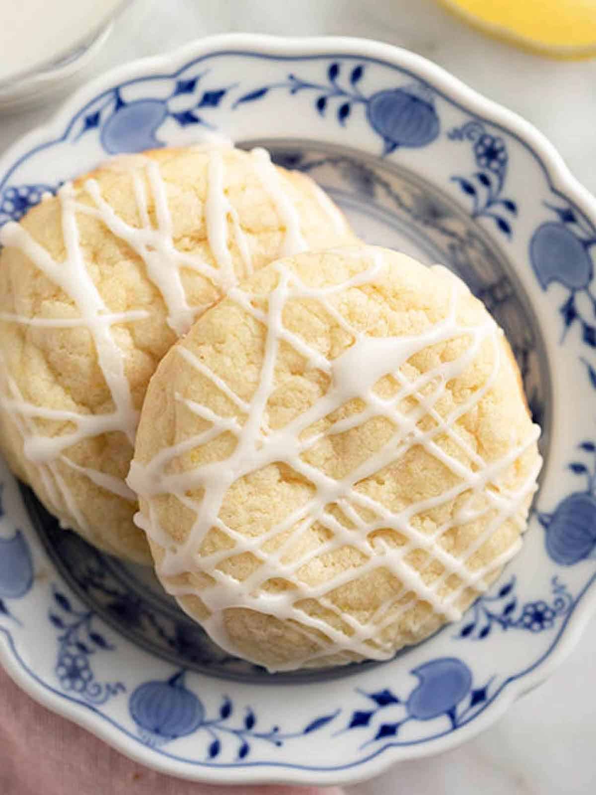 A plate with two lemon cookies with glaze drizzled.