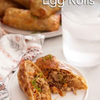 Pinterest graphic of a plate with an air fryer egg roll cut in half. A glass of ice water and platter of more air fryer egg rolls in the background.