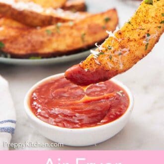 Pinterest graphic of an air fryer potato wedge dipped into a bowl of ketchup.