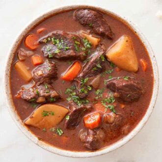 Overhead view of a bowl of beef stew topped with chopped parsley.