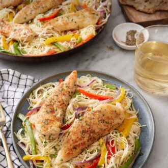 Pinterest graphic of chicken scampi on a plate with a glass of wine, a loaf of bread, and skillet with more chicken scampi in the background.
