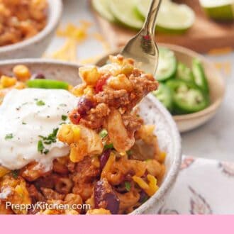 Pinterest graphic of a forkful of chili mac being lifted from a bowl.