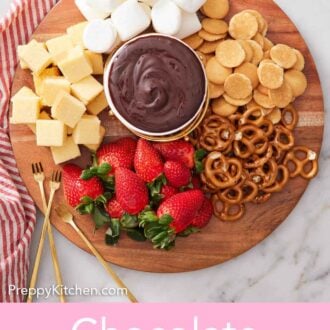Pinterest graphic of an overhead view of a spread with a bowl of chocolate fondue in the middle surrounded by strawberries, pretzels, cake, marshmallows, and cookies.