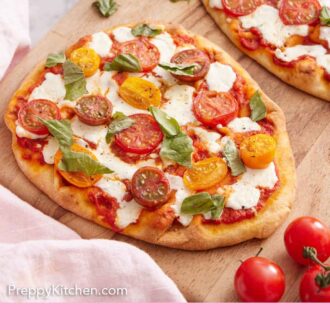 Pinterest graphic of a wooden serving board with two flatbread pizzas topped with fresh basil.