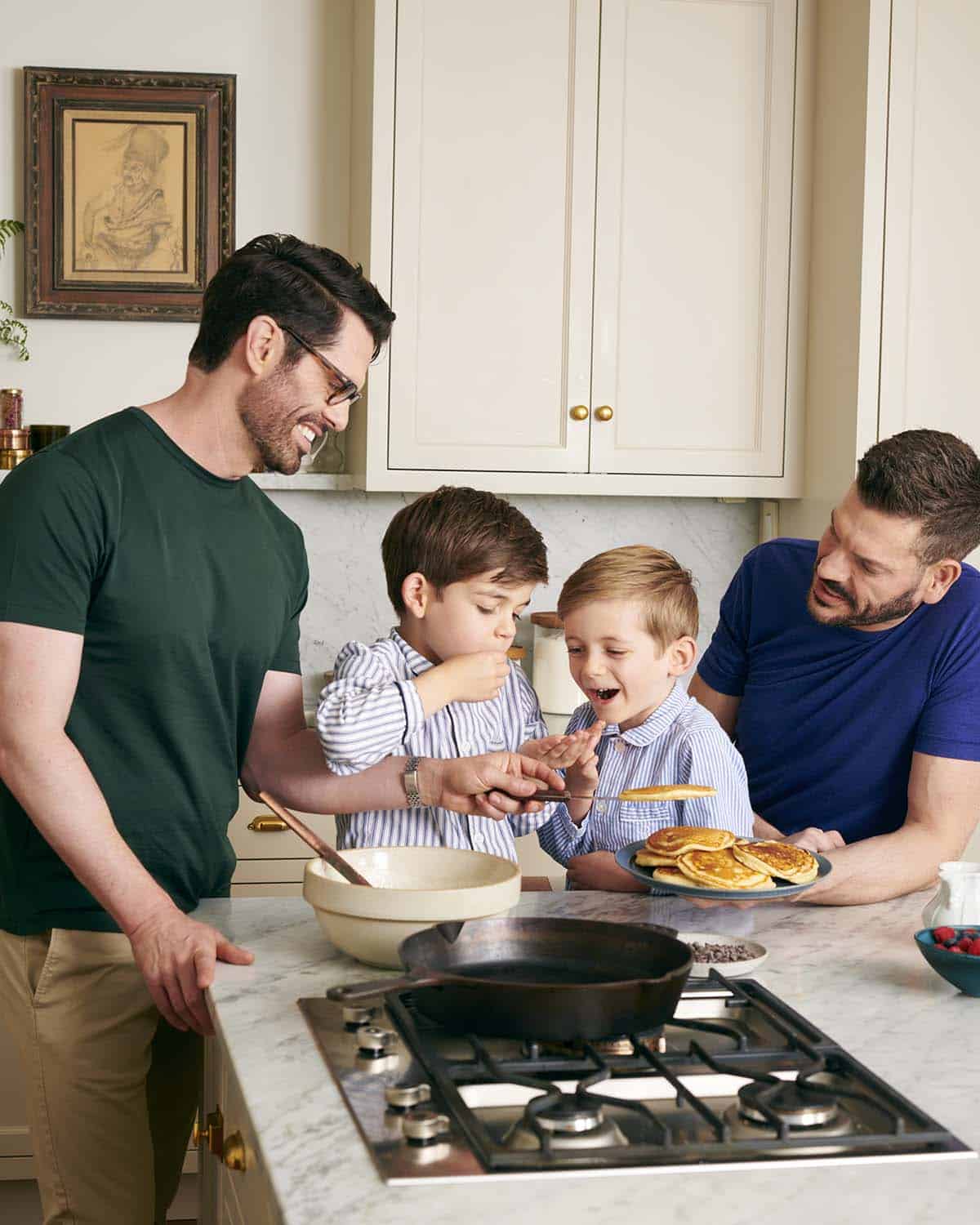 John Kanell with this husband and two boys making pancakes in the kitchen.