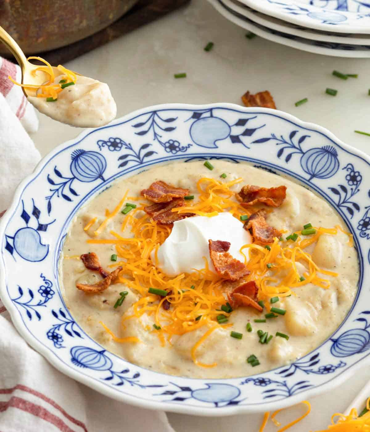 A bowl of potato soup with a spoonful lifted out.