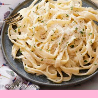Pinterest graphic of fettucine alfredo on a plate with a fork beside it. Chopped parsley and shredded parmesan on top.
