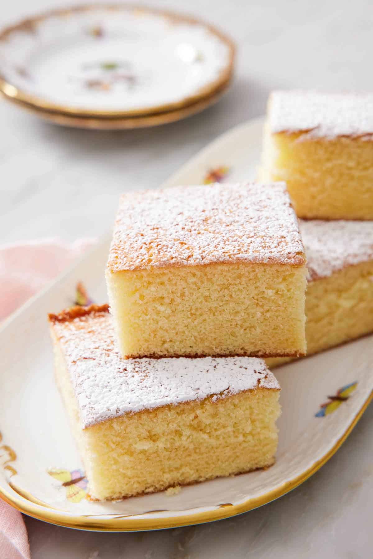 A platter of hot milk cake pieces, some stacked on top of each other.