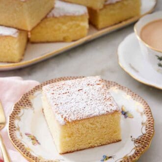 Pinterest graphic of a slice of hot milk cake topped with a dusting of powdered sugar. A platter with more pieces in the back.
