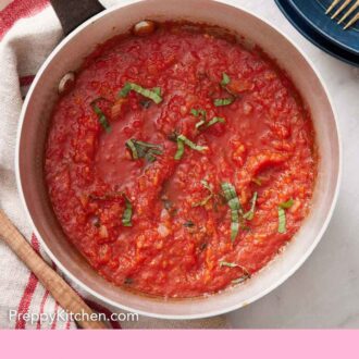 Pinterest graphic of a pot of marinara sauce with some fresh ribboned basil as garnish.
