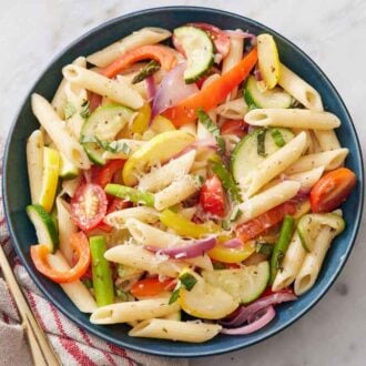 Overhead view of a bowl of pasta primavera with a fork on the side.