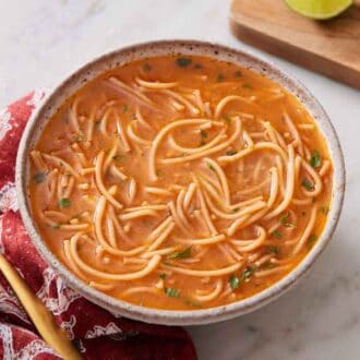 A bowl of sopa de fideo with a spoon beside it.