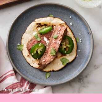 Pinterest graphic of an overhead view of a tortilla with sliced steak, parsley, and jalapenos.