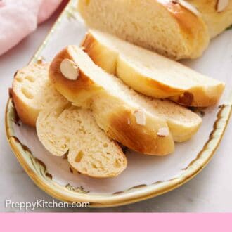 Pinterest graphic of a platter with a loaf of tsoureki with three slices cut in front.